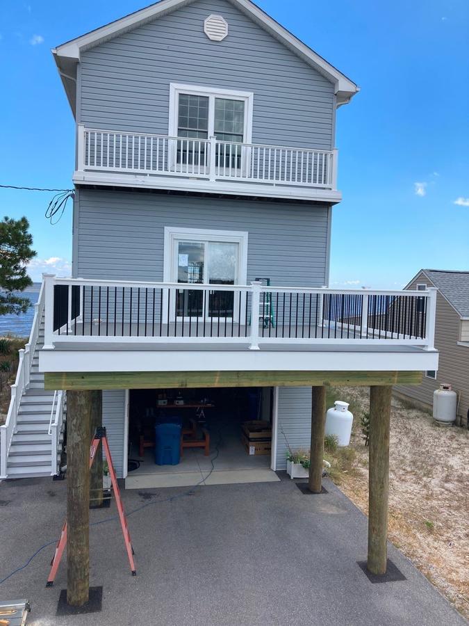 Elevated coastal home with a new upper-level deck and white railing